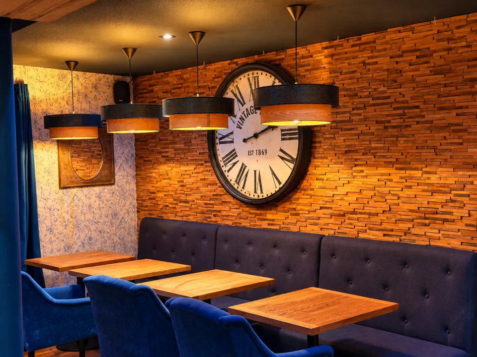 La salle du P’tit Couz’ : banquette, fauteuils en velours bleu et grande horloge